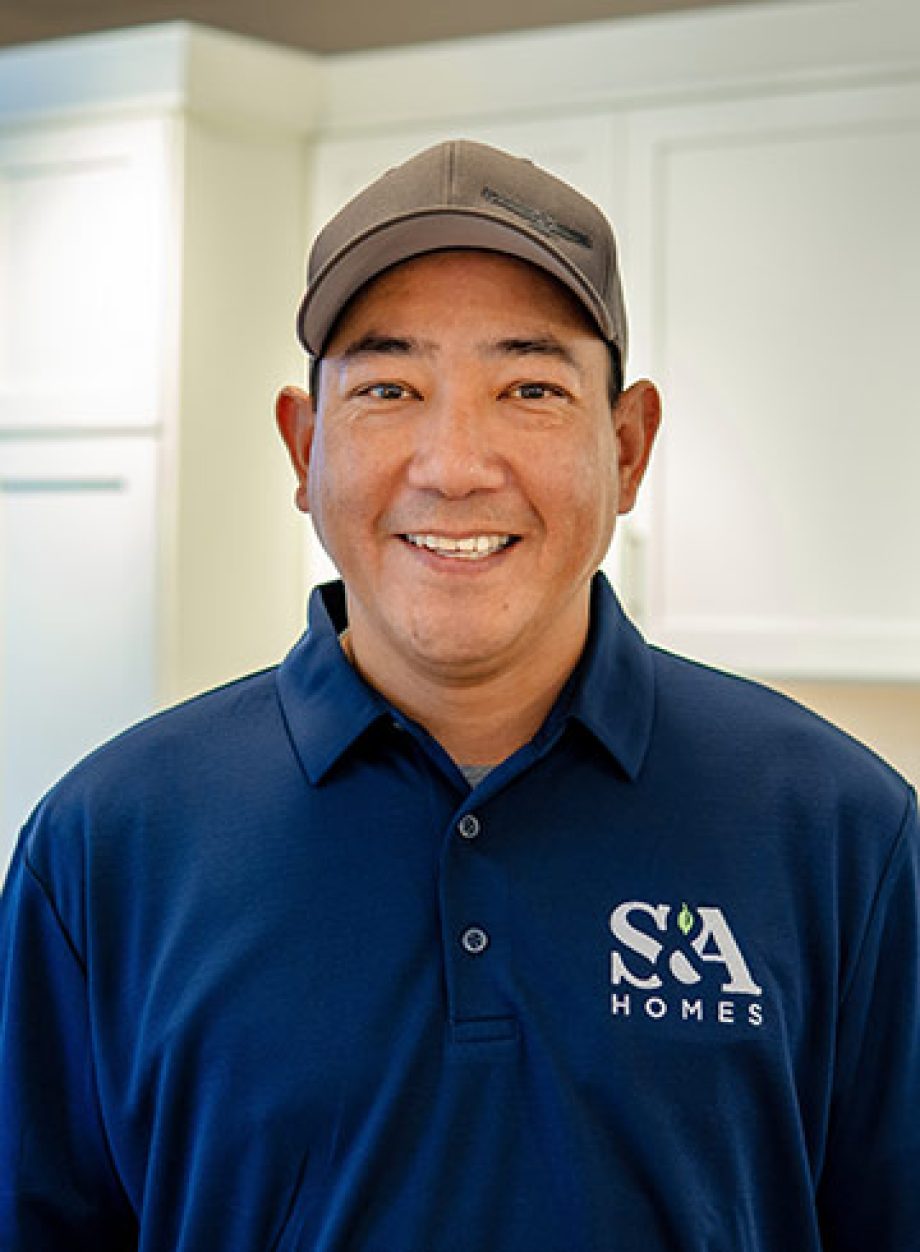 Joe Ladrido smiling indoors in a blue S&A Homes polo shirt and gray cap