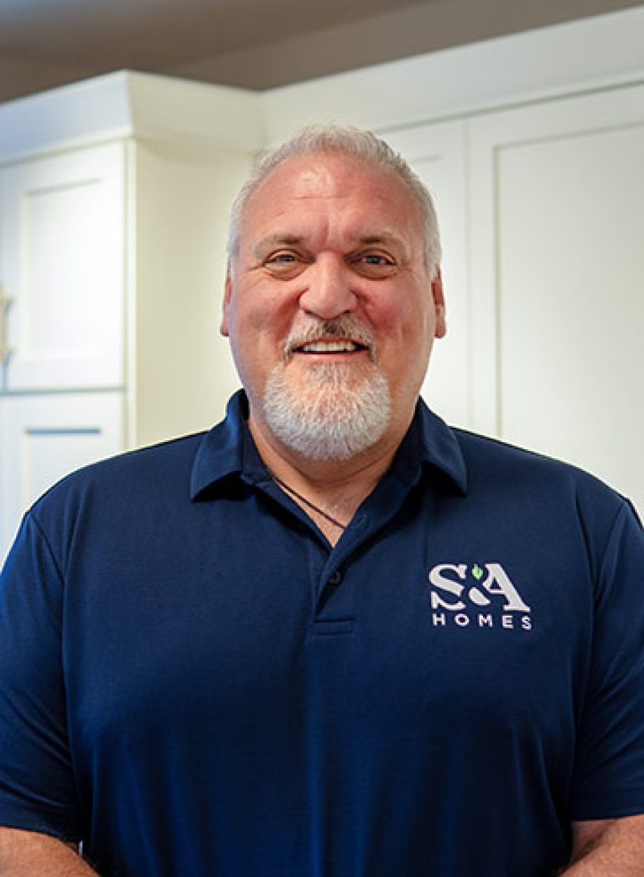 Tom Seaman smiling indoors in a navy S&A Homes polo shirt